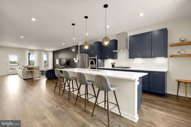 a kitchen with stainless steel appliances granite countertop a kitchen island a stove a sink a oven a dining table and chairs with wooden floor