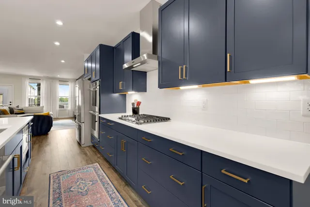 a kitchen with stainless steel appliances granite countertop a sink a stove and a wooden floors