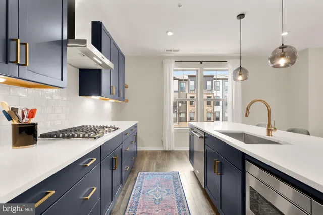 a kitchen with stainless steel appliances granite countertop a sink a stove and a wooden floors