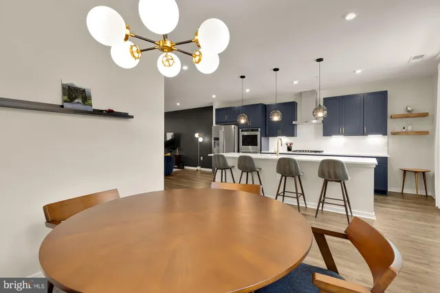 a living room with dining table a chandelier a sink and a mirror