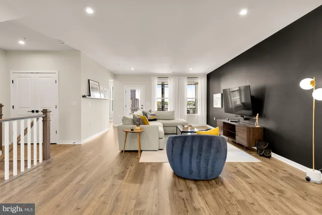a living room with furniture a flat screen tv and a wooden floor
