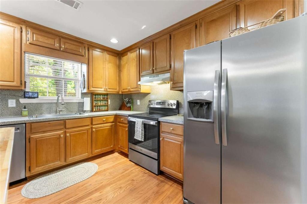 7210 Fields Drive Cumming, GA 30041 - Photo 22 of 58 a kitchen with stainless steel appliances granite countertop a refrigerator a sink dishwasher a stove with wooden cabinets and floor