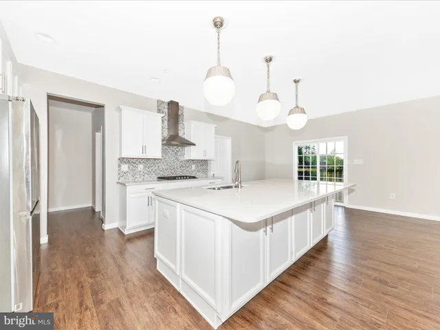 a kitchen with a stove a sink and wooden floor