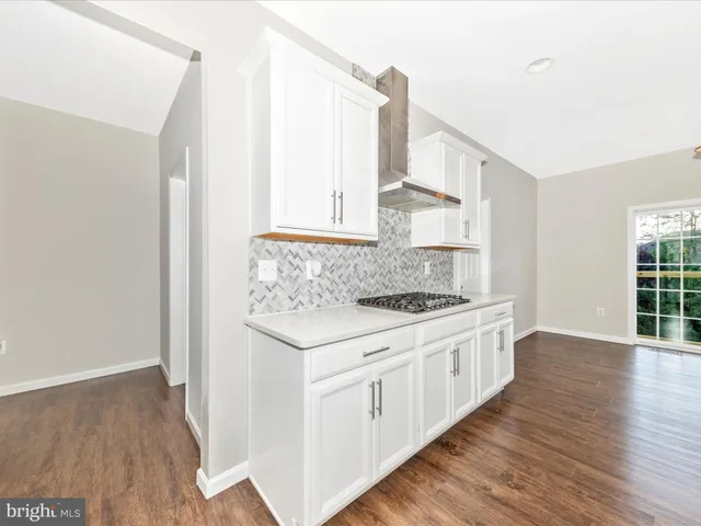 a large white kitchen with a large island oven a stove and white cabinets