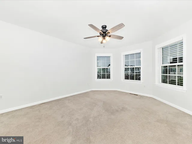 an empty room with chandelier fan and windows