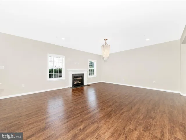 a living room with couches and kitchen view with wooden floor