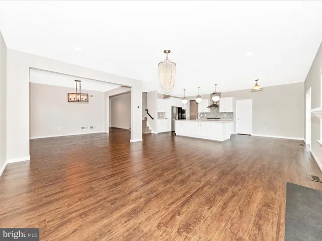a view of a hallway with wooden floor and a kitchen