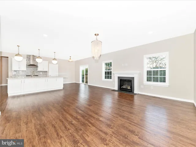 a view of an empty room with wooden floor fireplace and a window
