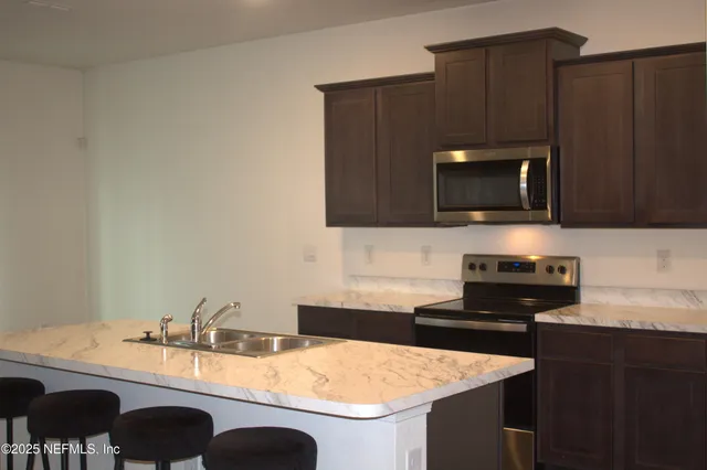 a kitchen with granite countertop a stove and a microwave with wooden floor