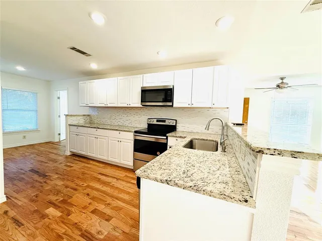 a kitchen with granite countertop a stove top oven sink and cabinets
