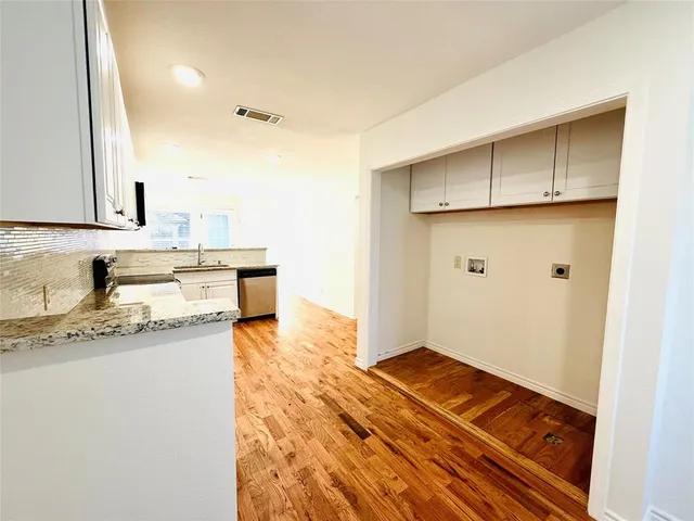 a large white kitchen with granite countertop a stove top oven a sink and dishwasher with wooden floor