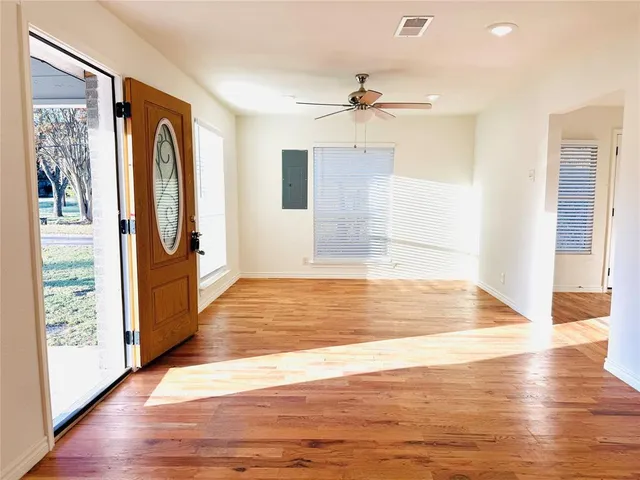a view of an empty room with wooden floor and a window