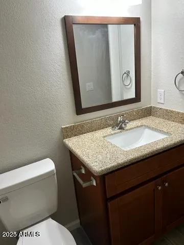 a bathroom with a granite countertop toilet sink and mirror