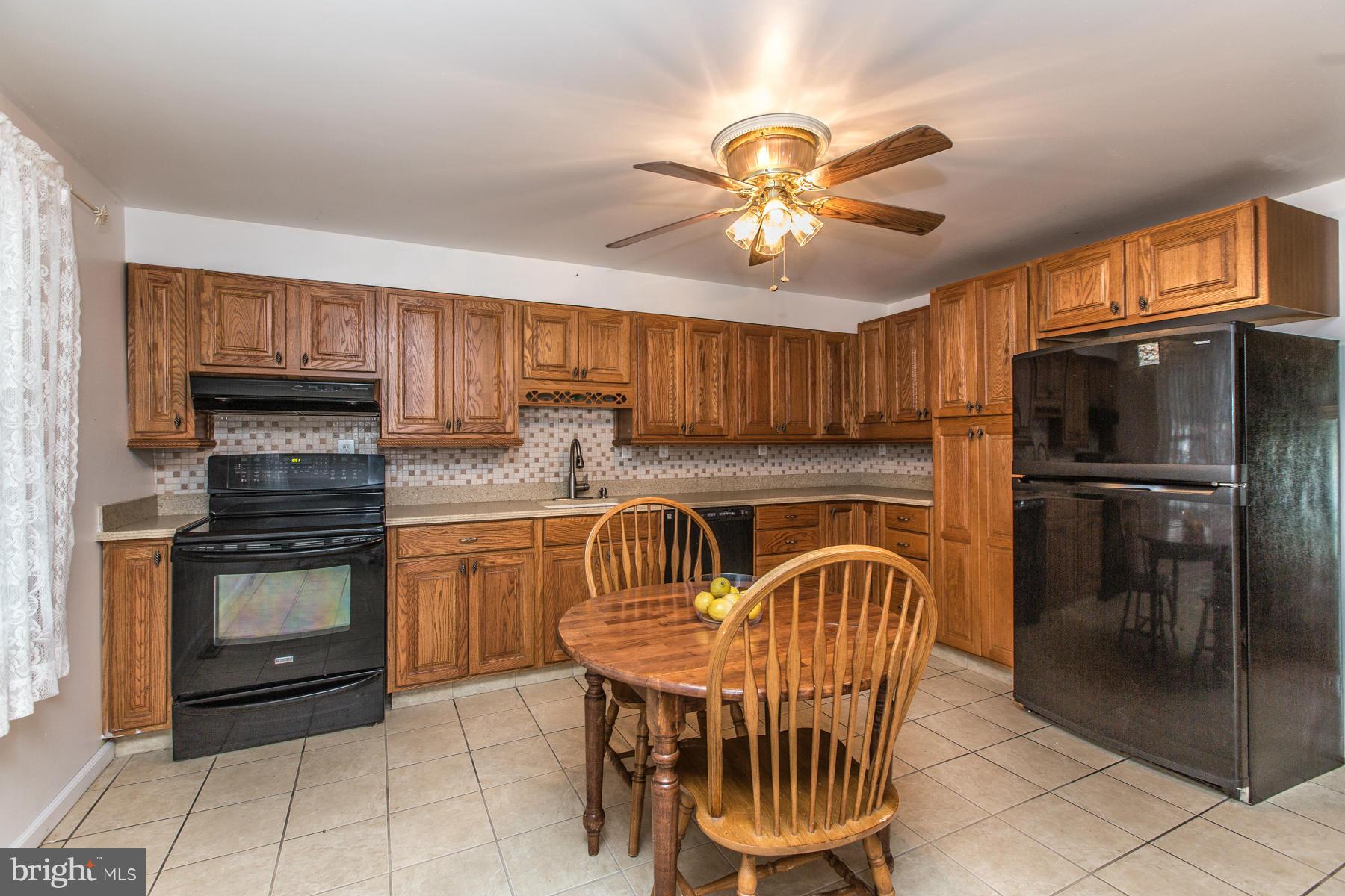 8009 Wynbrook Road Baltimore, MD 21224 - Photo 8 of 27 a kitchen with stainless steel appliances granite countertop a stove top oven a refrigerator a sink a dining table and chairs with wooden floor