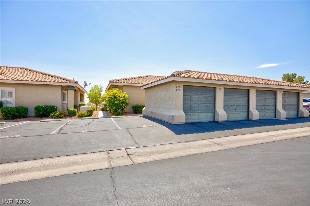 3238 Mystic Ridge Court Las Vegas, NV 89129 - Photo 24 of 31 A row of single-story residences with terracotta-tiled roofs and attached garages.