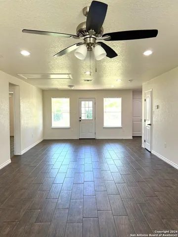 a view of an empty room with window and wooden floor