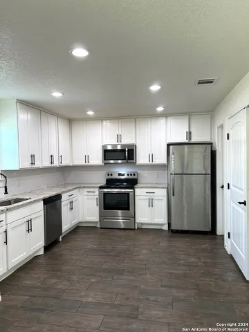 a kitchen with stainless steel appliances granite countertop a refrigerator sink and white cabinets