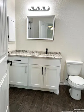 a bathroom with a toilet a sink and wooden floor