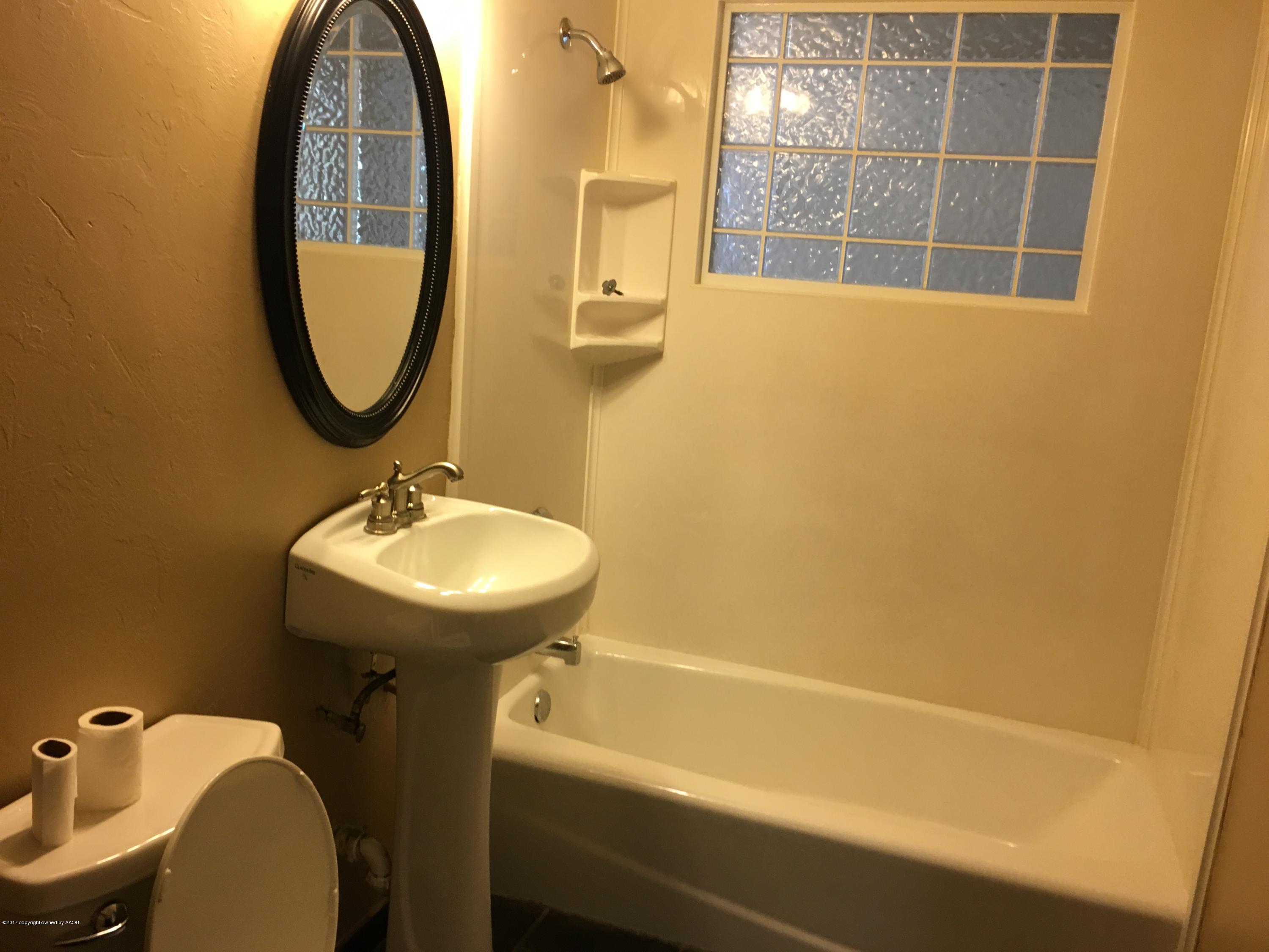 4651 Crockett Street Amarillo, TX 79110 - Photo 13 of 18 a bathroom with a sink a toilet and a mirror