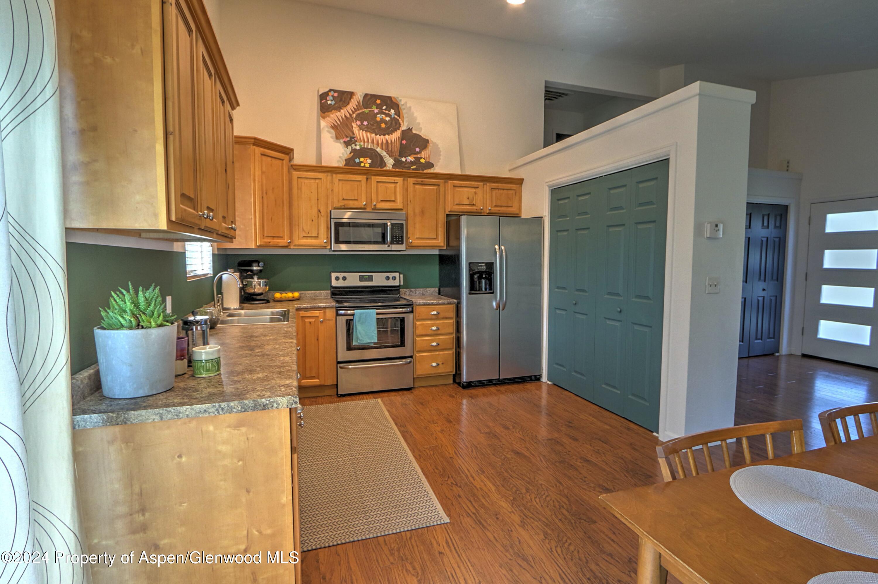 1329 East 8th Street Rifle, CO 81650 - Photo 11 of 26 a kitchen with stainless steel appliances granite countertop a refrigerator a stove and a wooden floors