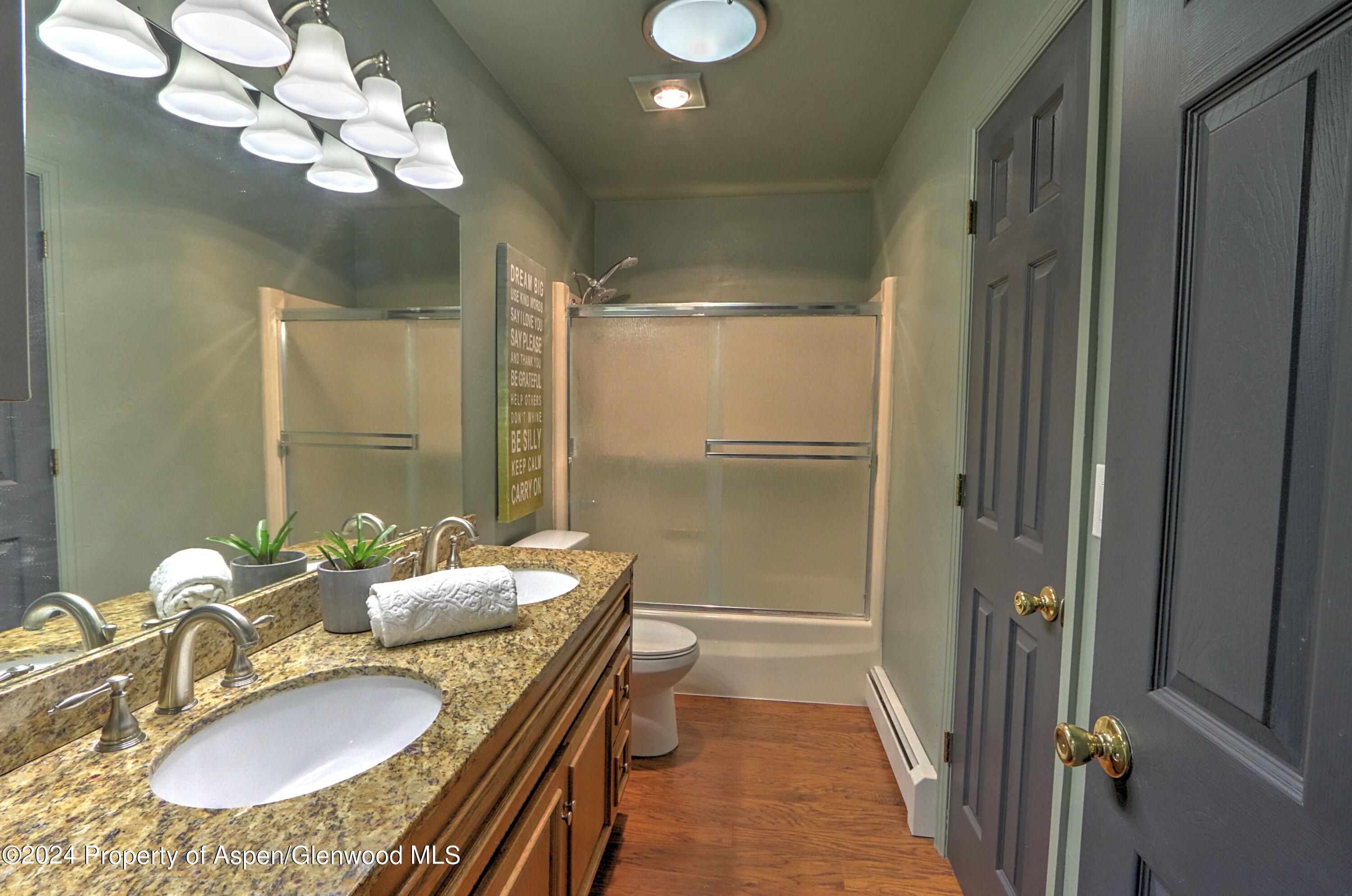 1329 East 8th Street Rifle, CO 81650 - Photo 15 of 26 a bathroom with a granite countertop sink a mirror and a shower
