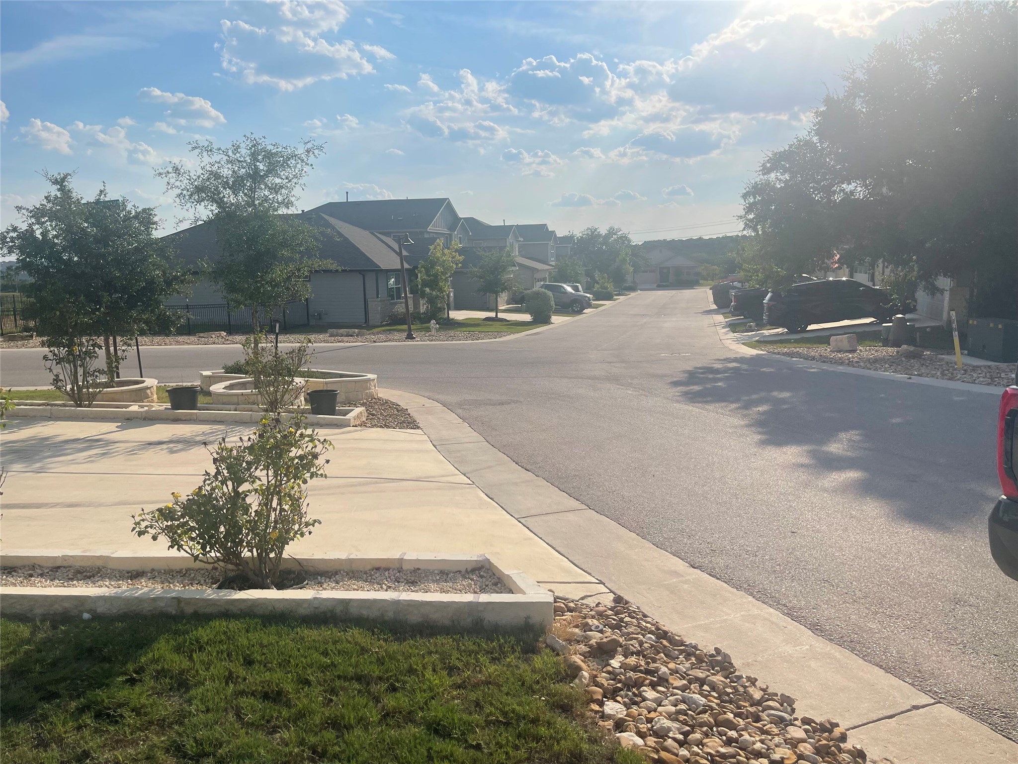 145 Merrick Road Georgetown, TX 78628 - Photo 3 of 32 Neat curbs and paved sidewalks line this quiet suburban street under a bright sky.
