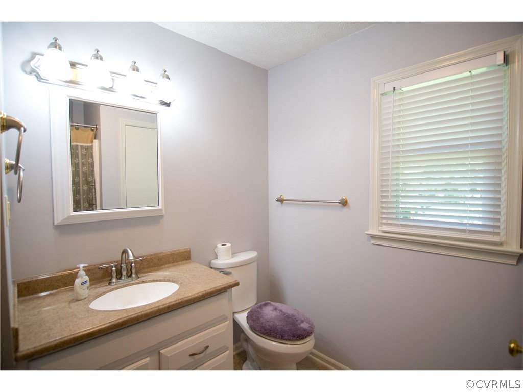 9361 West Bunker Hill Road Rice, VA 23966 - Photo 18 of 39 a bathroom with a granite countertop sink toilet a mirror and a window