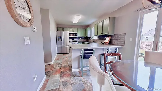 a living room with stainless steel appliances furniture a rug and a kitchen view