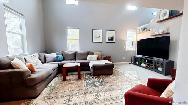 a living room with furniture a flat screen tv and a window