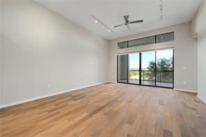 Gleaming wood floors and a soaring ceiling define this airy living space opening to a balcony.