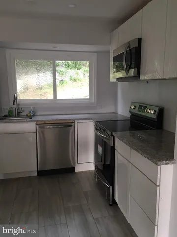 a kitchen with a stove and a white wooden cabinets