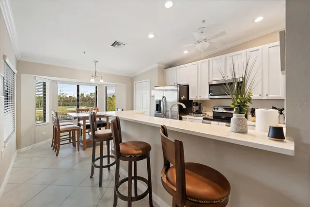 a kitchen with stainless steel appliances granite countertop a stove a sink a refrigerator white cabinets with a dining table and chairs