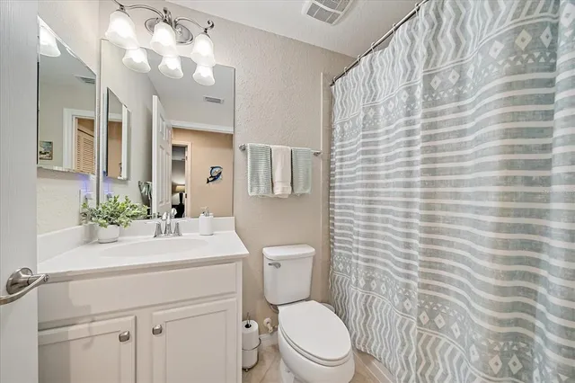 a bathroom with a sink a toilet a mirror and shower curtain