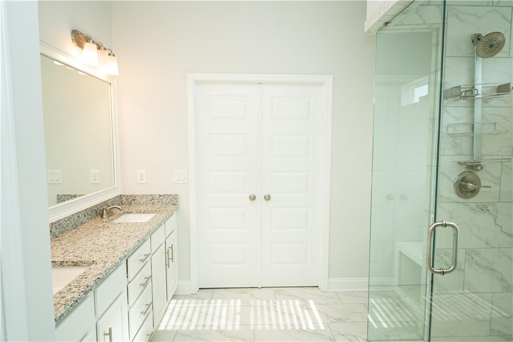 536 Sageton Court Grayson, GA 30017 - Photo 27 of 37 a bathroom with a granite countertop sink a mirror and shower