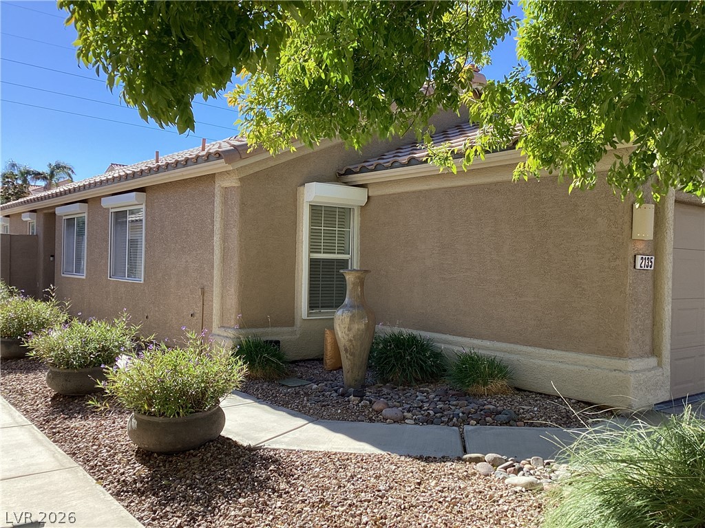 2135 Hidden Ranch Terrace Henderson, NV 89052 - Photo 2 of 27 A welcoming walkway leads to this well-maintained residence, featuring mature landscaping and a tiled roof.