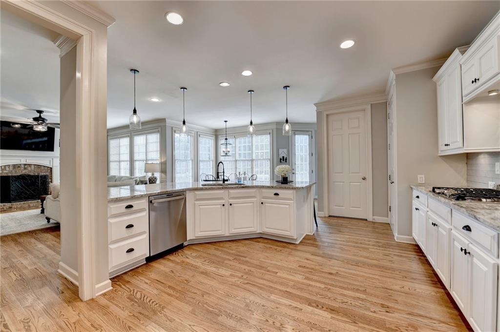 7051 Dove Point Lane Hoschton, GA 30548 - Photo 13 of 74 a large kitchen with granite countertop a large stove a sink dishwasher and a refrigerator with wooden floor
