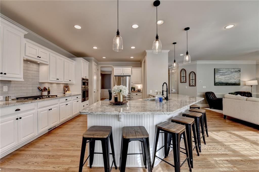 7051 Dove Point Lane Hoschton, GA 30548 - Photo 18 of 74 a large kitchen with stainless steel appliances kitchen island granite countertop a dining table chairs and white cabinets