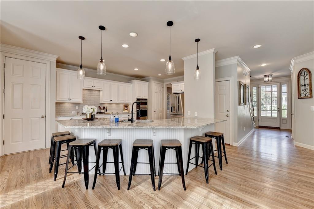 7051 Dove Point Lane Hoschton, GA 30548 - Photo 19 of 74 a kitchen with stainless steel appliances granite countertop a kitchen island a stove a sink a oven a dining table and chairs