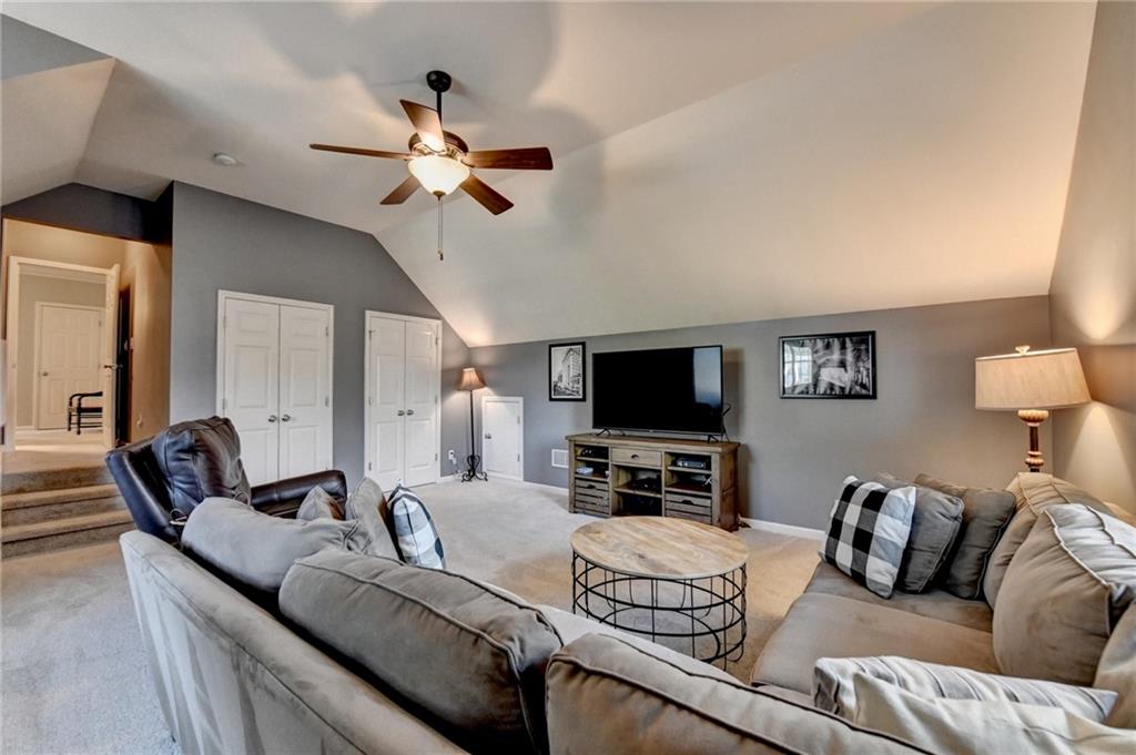 7051 Dove Point Lane Hoschton, GA 30548 - Photo 43 of 74 a living room with furniture a flat screen tv and a chandelier