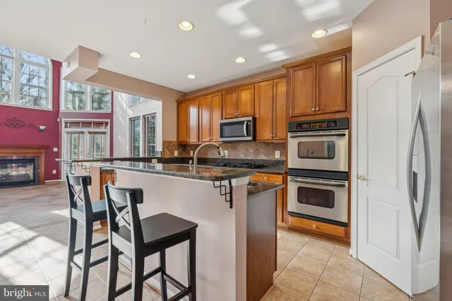 a kitchen with stainless steel appliances granite countertop a stove a refrigerator a oven a sink with a dining table and chairs