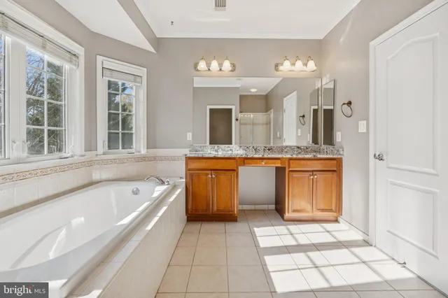 a spacious bathroom with a granite countertop sink mirror and bathtub