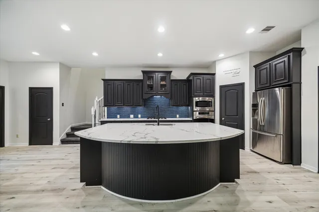 a large kitchen with kitchen island a sink stainless steel appliances and cabinets