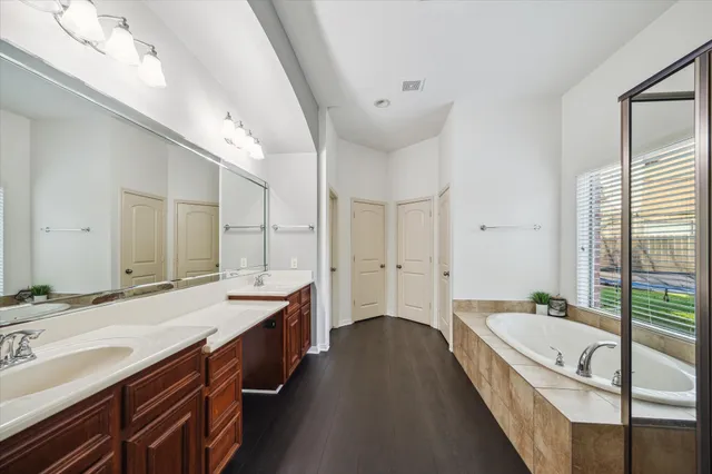 a spacious bathroom with a granite countertop double vanity sink a mirror and a bathtub