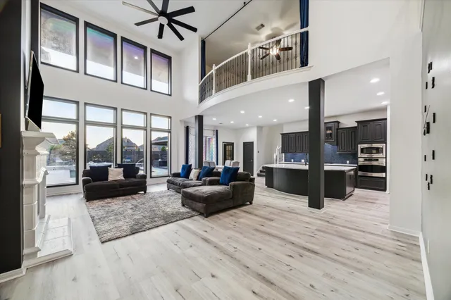 a living room with stainless steel appliances kitchen island granite countertop a refrigerator a stove and a wooden floors