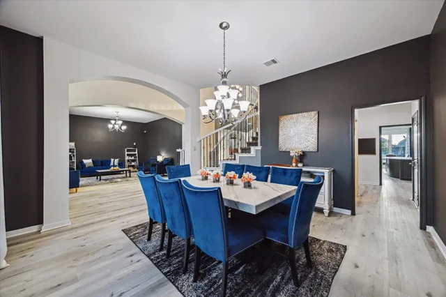 a dining room with wooden floor a chandelier a wooden table and chairs