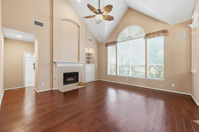 a view of empty room with wooden floor and fan