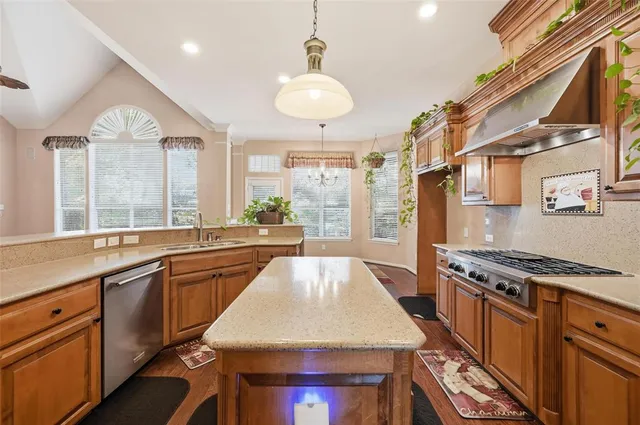 a kitchen with stainless steel appliances granite countertop a stove a sink dishwasher and a refrigerator with wooden floor