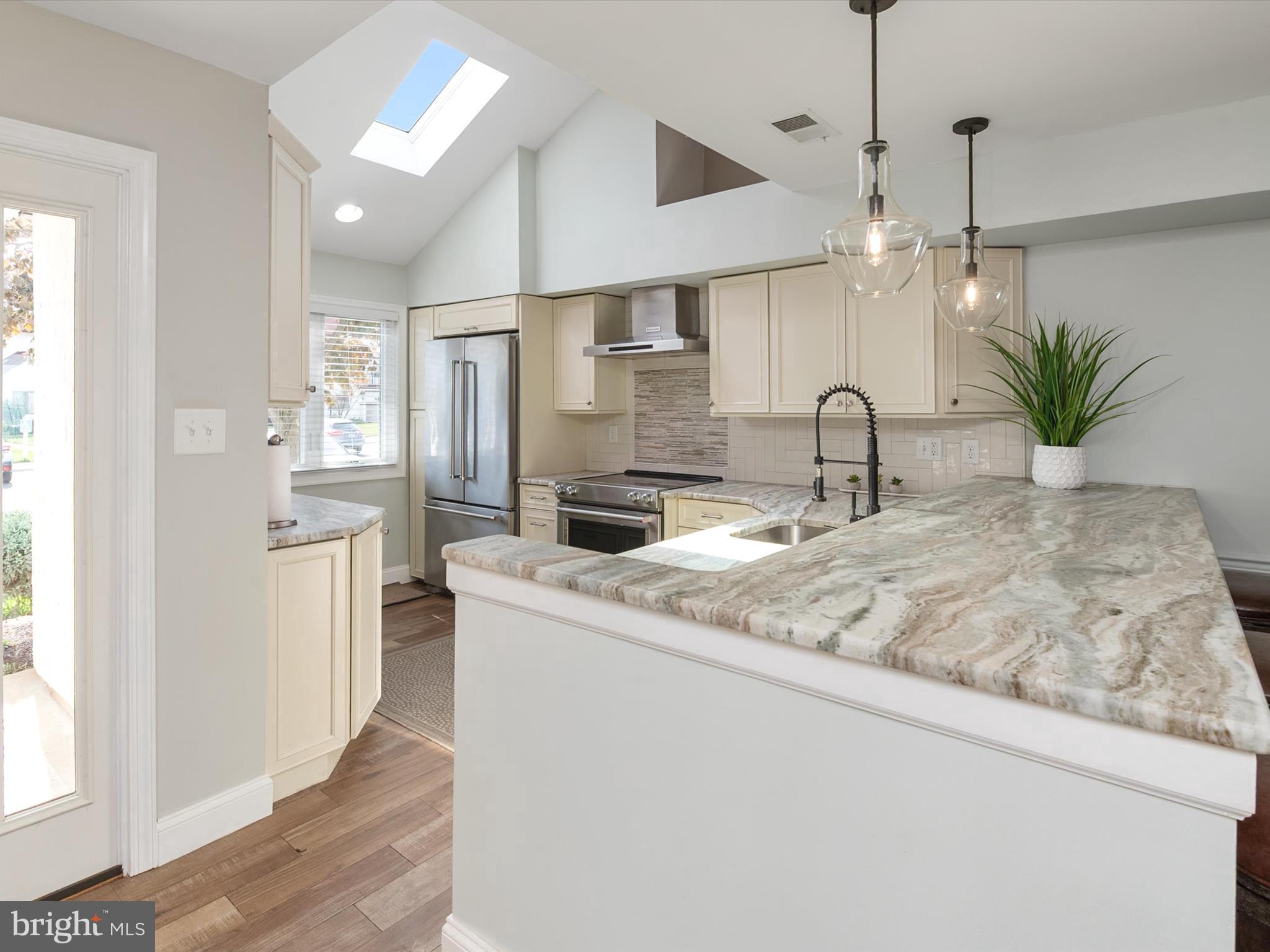 32 Queen Anne Way Chester, MD 21619 - Photo 9 of 61 a kitchen with stainless steel appliances granite countertop a sink a refrigerator a stove a dining table and chairs with wooden floor