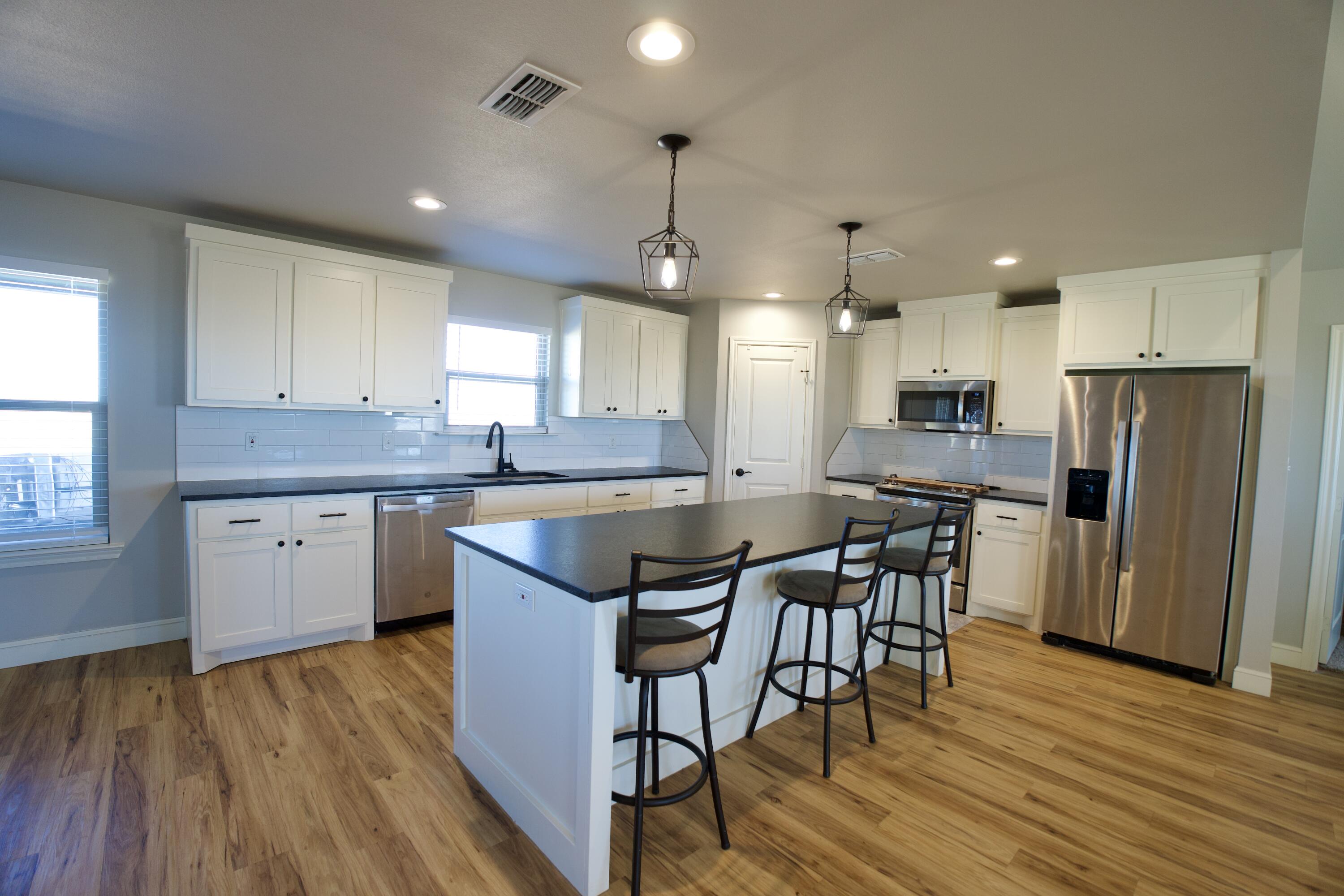7405 County Road 3700 Slaton, TX 79364 - Photo 4 of 26 a kitchen with stainless steel appliances granite countertop wooden floor sink dining table and chairs