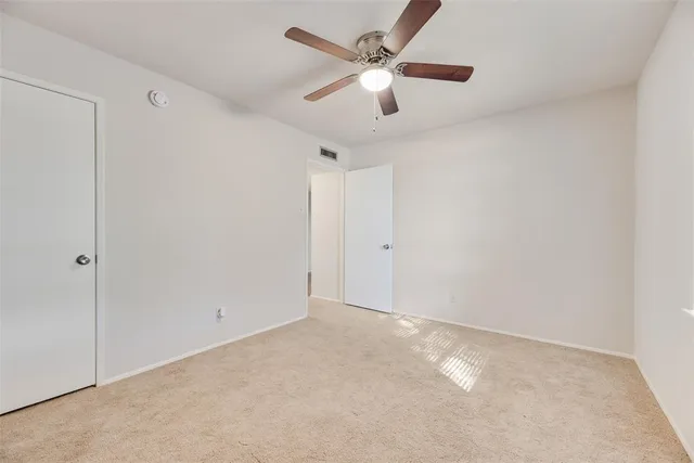 an empty room with a ceiling fan and a window